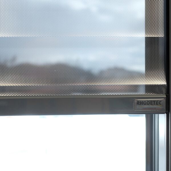 Close-up of a roller shade with RHODESHADE solar control film at the window