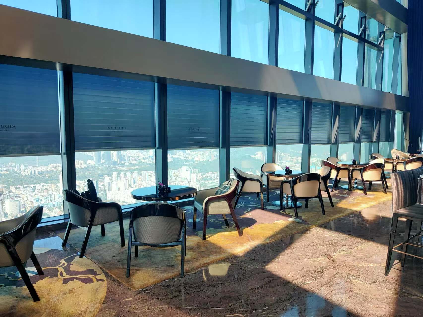 Lounge on the 96th floor of The St. Regis Shenzhen with roller shades along the glass façade