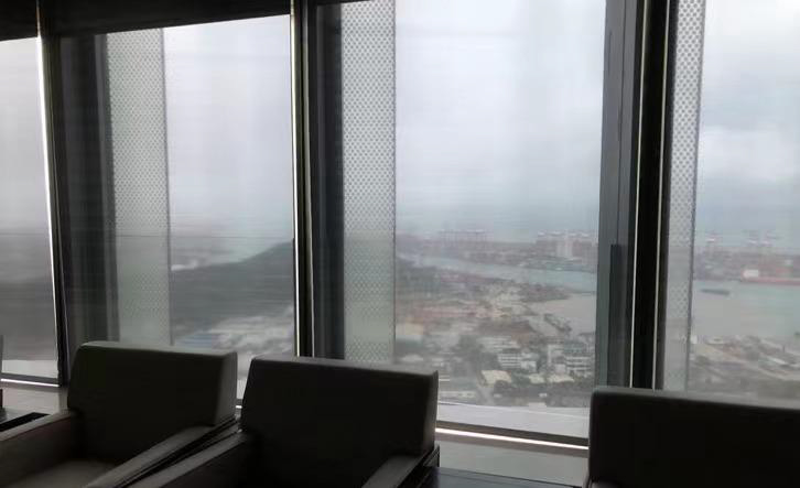 ChiWan Headquarters Building in Shenzhen: seating area at the window front with roller shades and a view of the port
