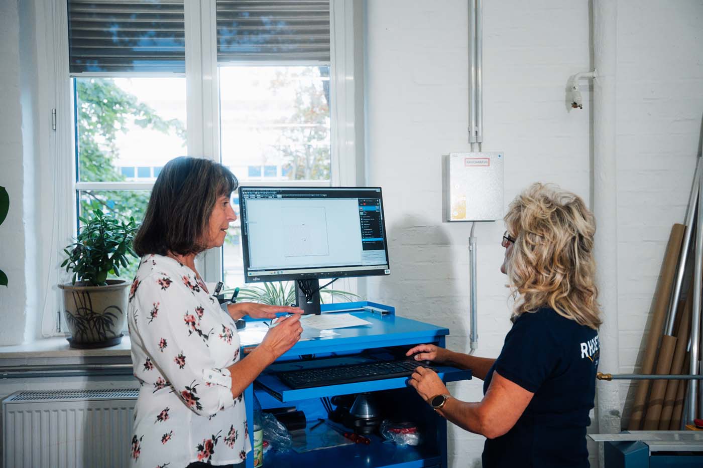 Two RHODETEC employees at a workstation with a monitor in production
